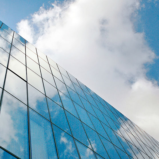 Edificio acristalado mirado desde abajo con el cielo y nubes de fondo
